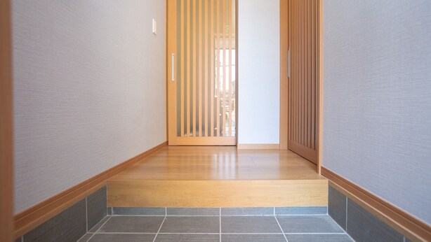 Un pasillo con piso de madera, una puerta corredera y paredes con azulejos.