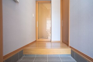 Un pasillo con piso de madera, una puerta corredera y paredes con azulejos.