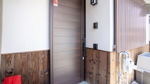 Una puerta de madera con un letrero, una luz empotrada en la pared y un calentador de agua.
