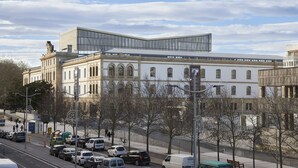 Moderni rakennus, jossa on klassinen julkisivu, lasinen lisäosa ja pysäköintialue autoineen.