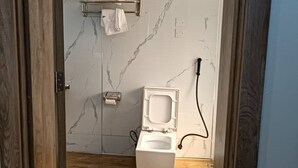 Een badkamer met toilet, handdoekhouder en een marmeren wand.