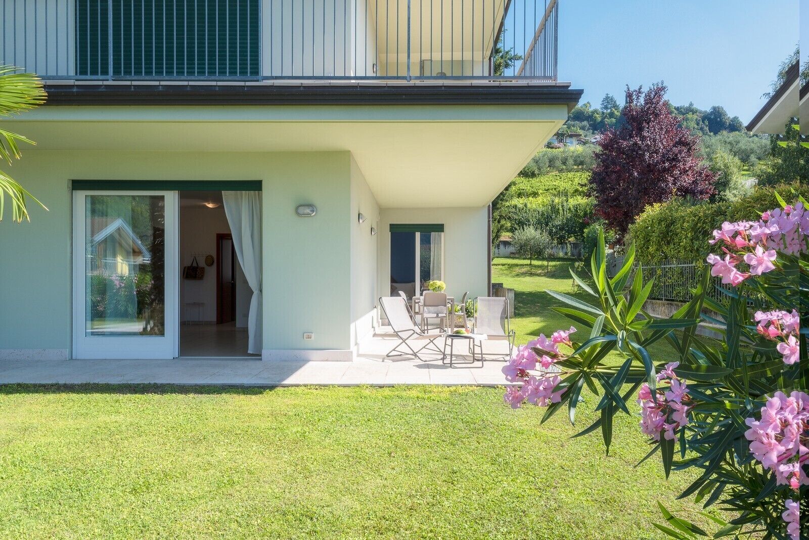 A modern house with a patio area featuring outdoor seating and a glass door entrance.