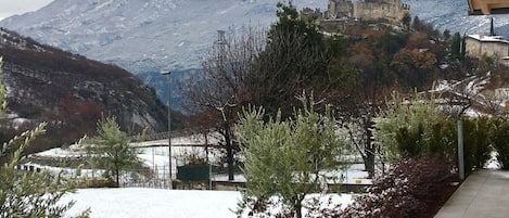 Vista de un castillo en una colina con paisaje nevado y un río al frente.