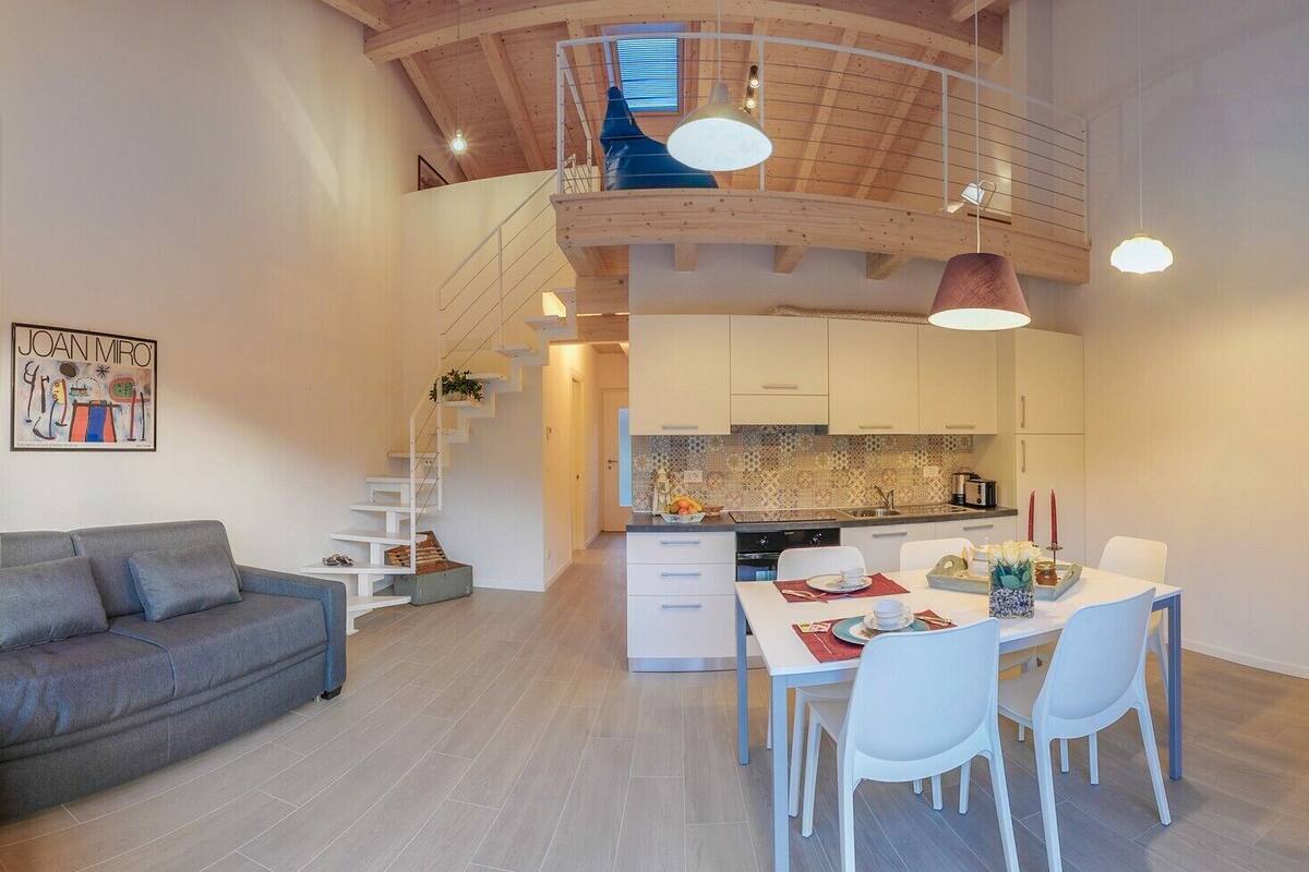 A modern apartment with a dining area, kitchen, and a staircase leading to an upper level.