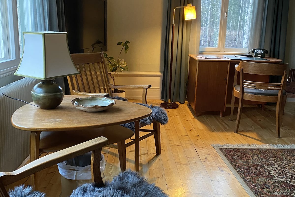 Ein gemütliches Zimmer mit einem Holzespeisetisch, Stühlen, einer Lampe und einem Fernseher.