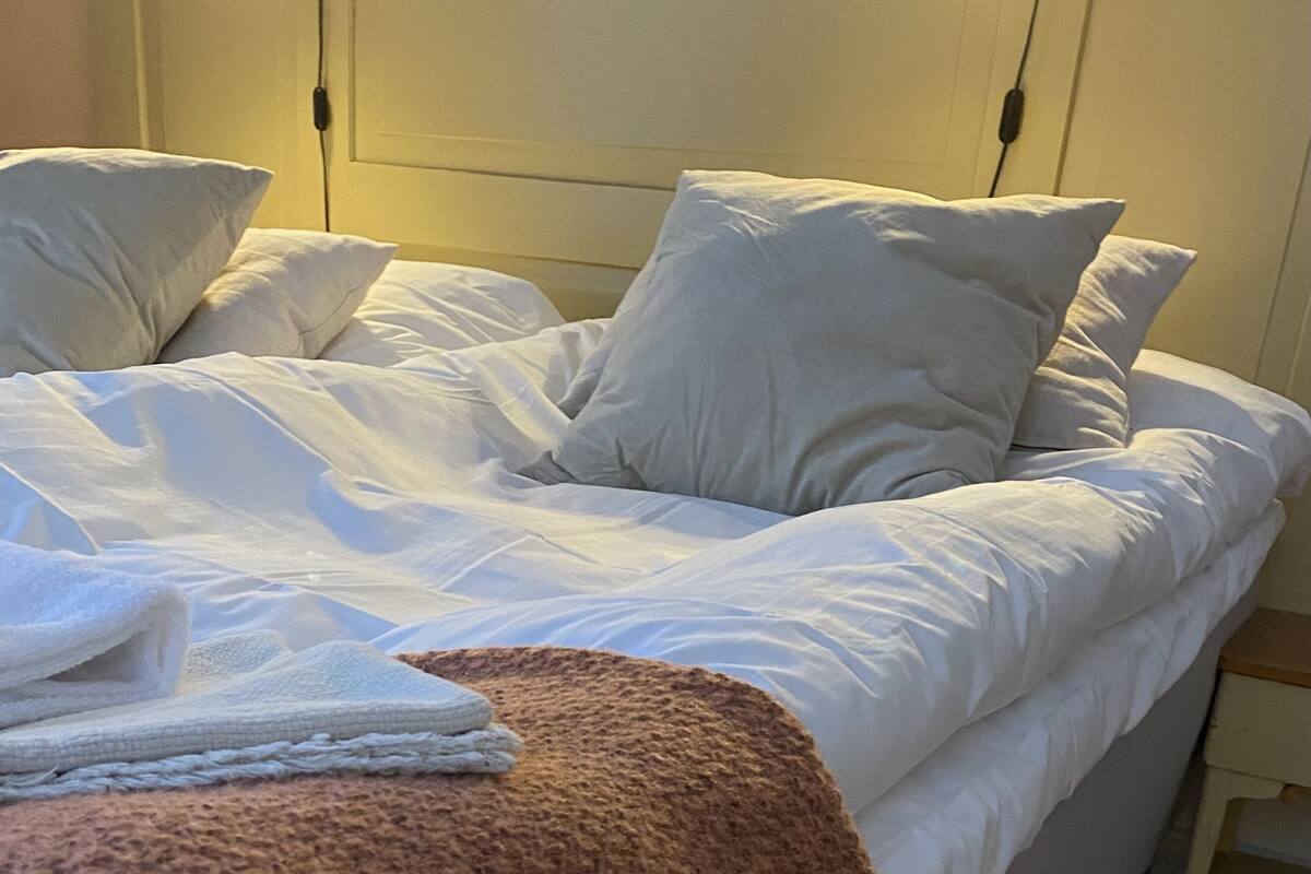 Ein Bett mit weißer Bettwäsche, zwei Nachttischlampen und ein gerahmtes Bild an der Wand.