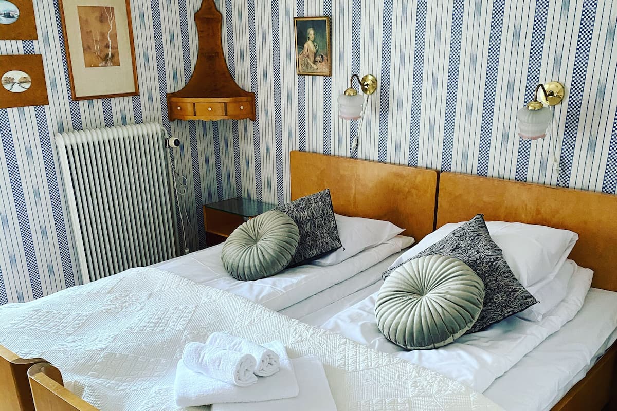 Ein Doppelbett mit Holz Kopfteil, zwei Kissen und einer weißen Bettdecke.