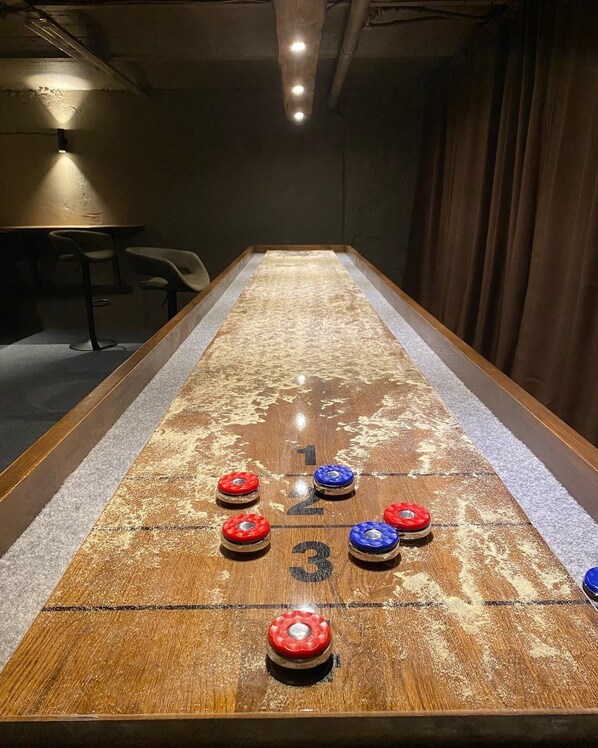A shuffleboard table with numbered scoring areas and pucks in red and blue.