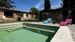 A swimming pool with lounge chairs, a stone building, and a tall tree in the background. - Magical: Completely renovated farmhouse in the middle of an olive grove (Cotignac)