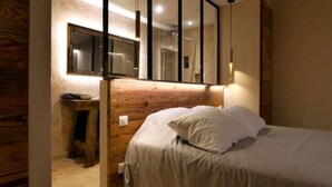 A bedroom with a wooden headboard, a bed with white linens, a bedside table, a mirror, and a small cabinet. - Magical: Completely renovated farmhouse in the middle of an olive grove (Cotignac)
