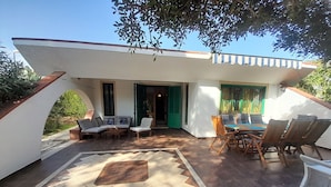 A modern outdoor patio area with a dining table and chairs, a sofa, and a patterned floor.