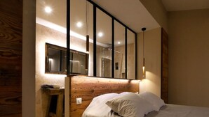 A bedroom with a wooden headboard, a bed with white bedding, a small bedside table, and a mirror above the bed. - Magic: the completely renovated stone Mazet (Cotignac)