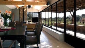 A spacious dining area with a large table and chairs, a vase with flowers, and a stone wall. - Magic: the completely renovated stone Mazet (Cotignac)