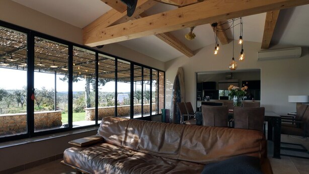 A spacious living room with a leather sofa, large windows, and a view of the outdoors. - Magic: the completely renovated stone Mazet (Cotignac)
