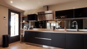 A modern kitchen with dark cabinetry, stainless steel appliances, and a large island. - Magic: the completely renovated stone Mazet (Cotignac)