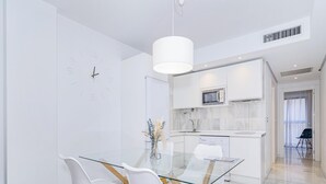 Moderni keittiö, jossa on valkoiset kaapit, mikroaaltouuni ja astianpesukone.