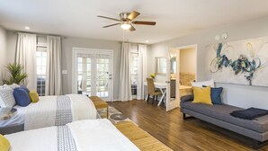 Une chambre moderne avec deux lits, un canapé, un ventilateur de plafond et un coin repas.