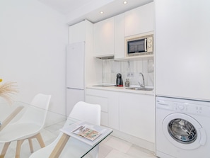 A compact kitchen with a microwave, coffee maker, and washing machine.