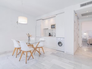 A modern kitchen with a microwave, coffee maker, and washing machine.
