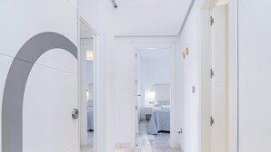 A hotel corridor with a modern design, featuring a glass door, a tiled floor, and a visible bedroom with a bed and nightstand. - Spacious and modern Apartment with free parking in the heart of Granada 10 (Granada)
