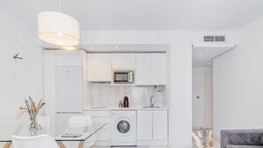 A modern kitchen with a microwave, sink, and washing machine. There is a dining area with a table and chairs. - Spacious and modern Apartment with free parking in the heart of Granada 10 (Granada)
