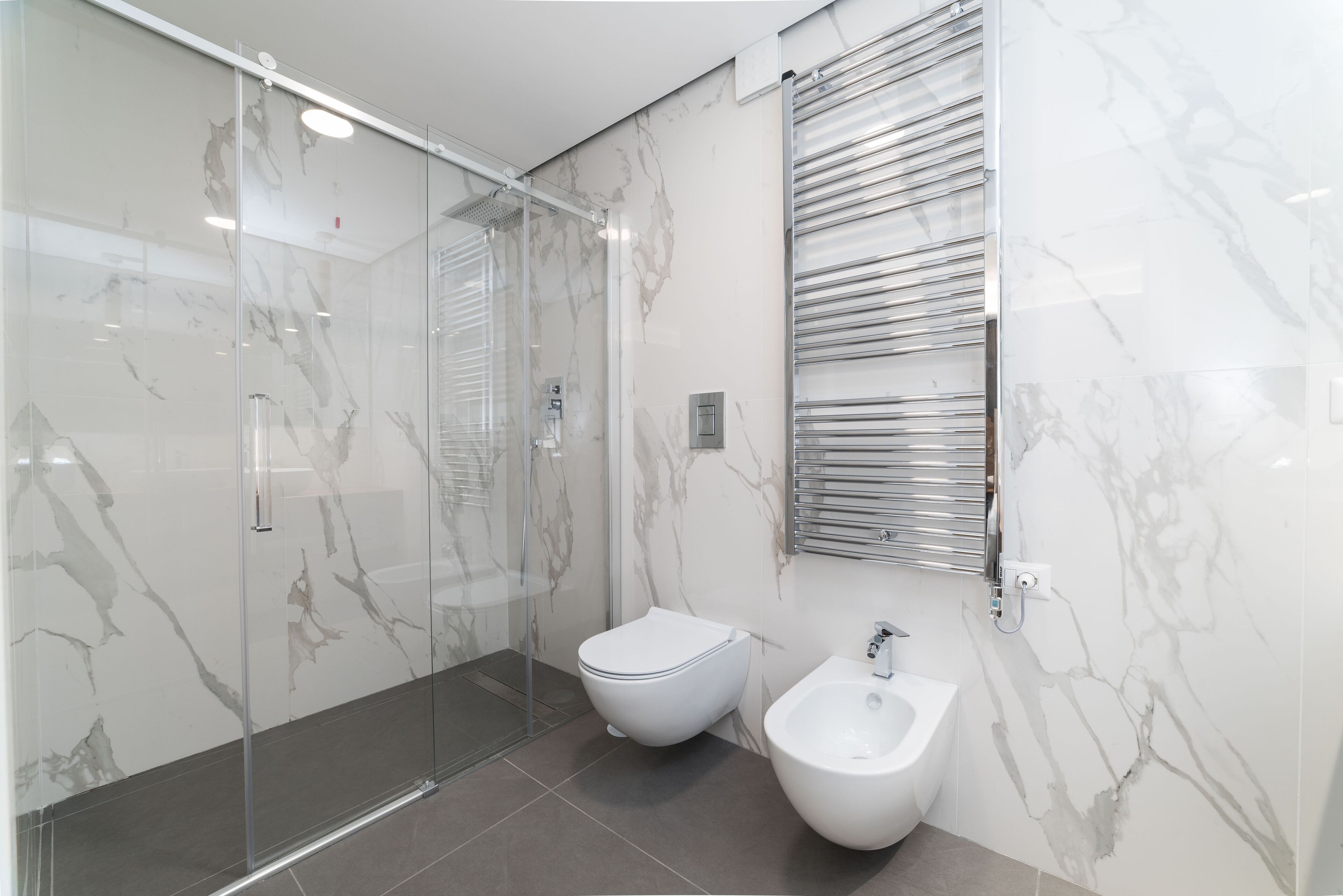 Un bany modern amb dutxa de vidre, un vàter i un bidet.