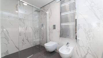 Un bany modern amb dutxa de vidre, un vàter i un bidet.