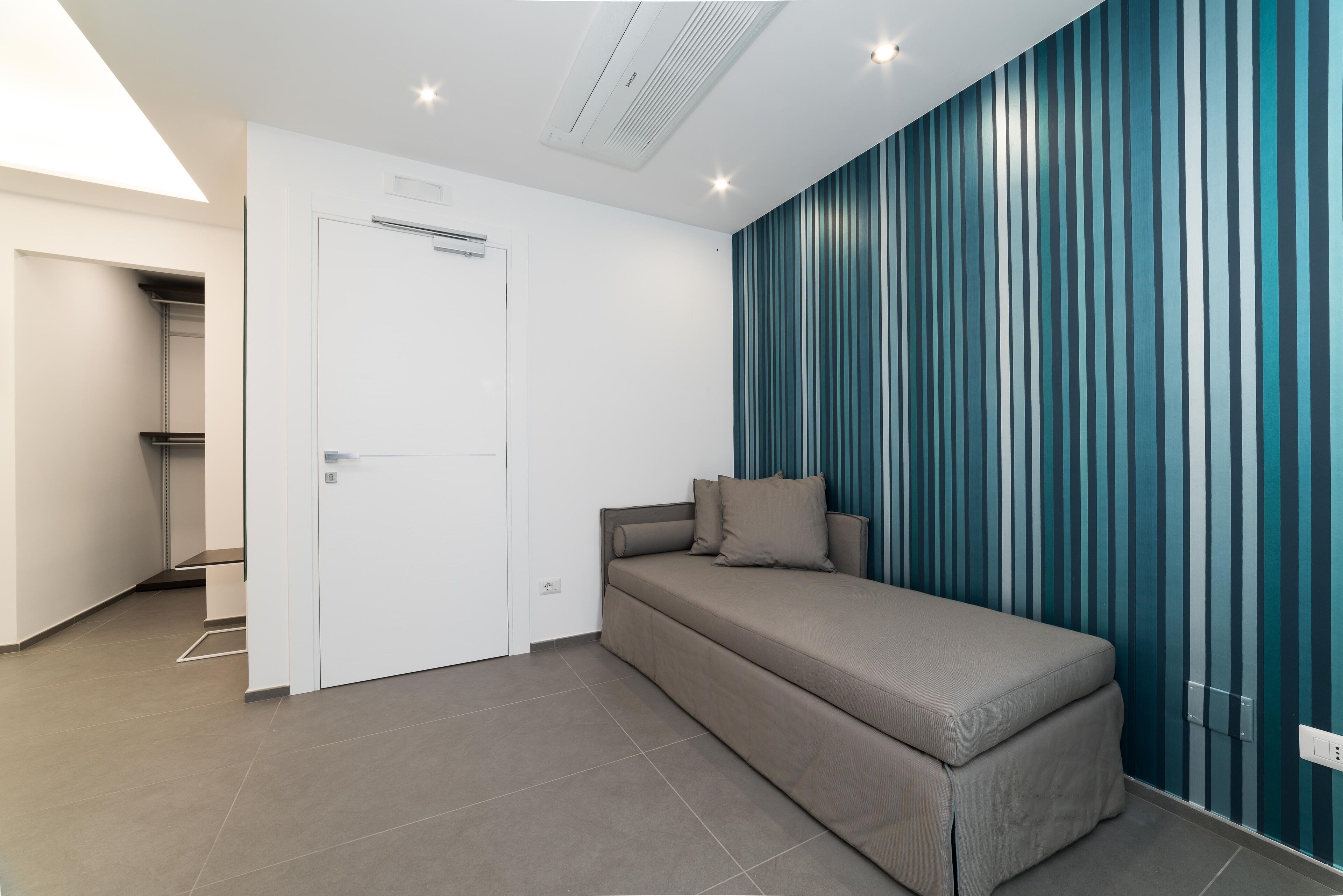 Una habitación moderna con sofá cama, una puerta y una pared a rayas.