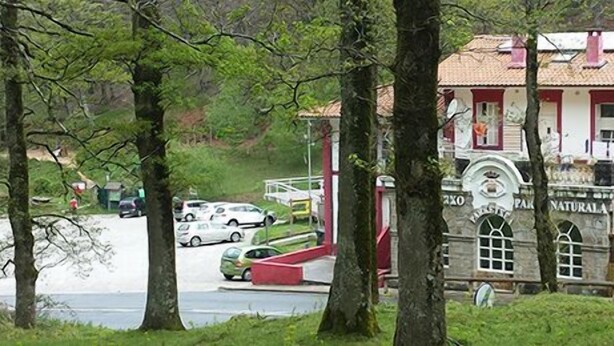 A two-story building with a red and white facade, a tiled roof, and a small balcony. - Lizarrusti Parketxea - Hostel (Ataun)