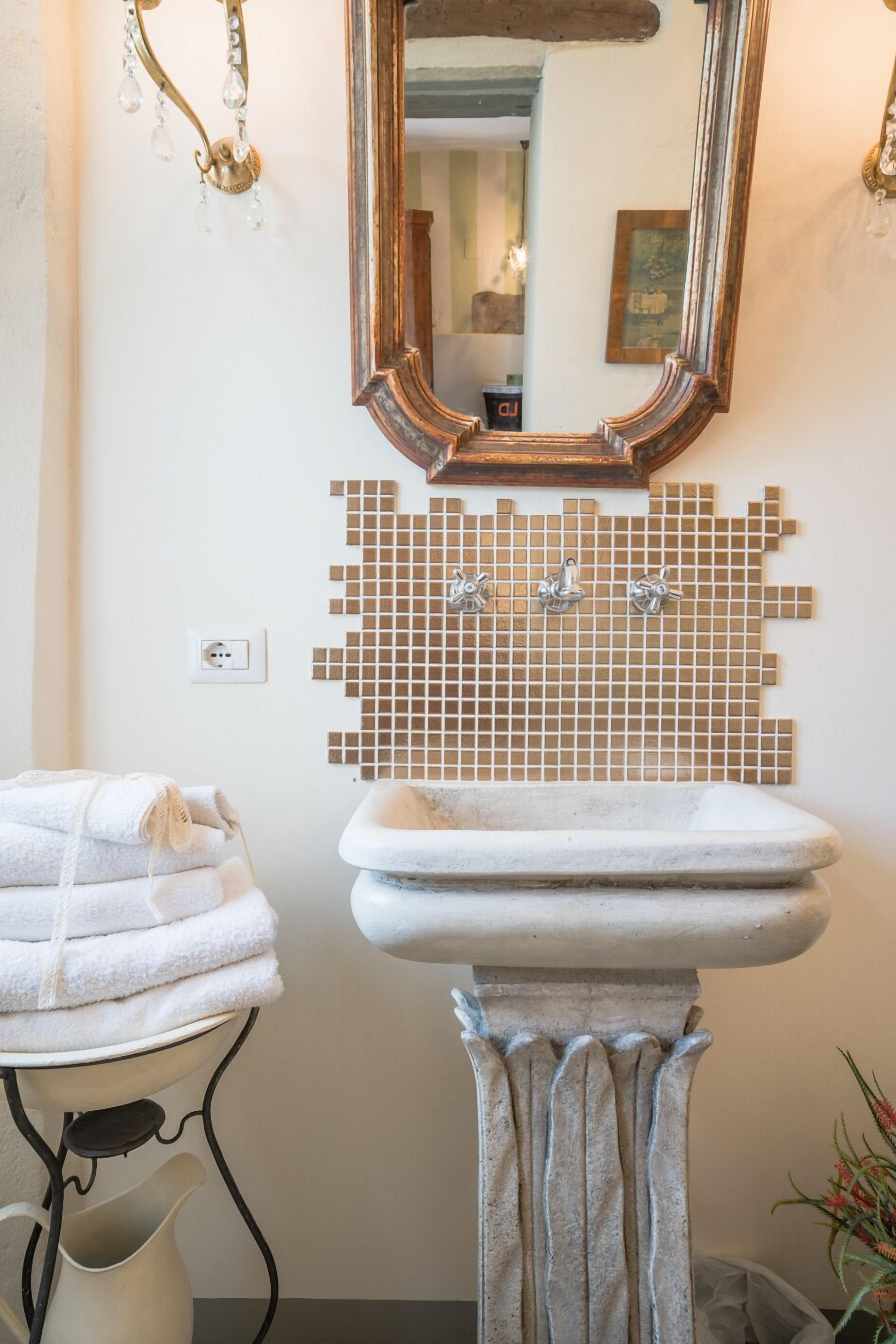 A bathroom with a white sink, a mirror with a wooden frame, and a mosaic tile backsplash.