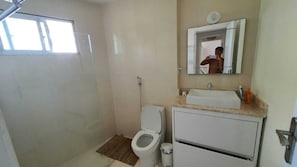 Ein kleines Badezimmer mit Toilette, Waschbecken, Spiegel und Dusche.