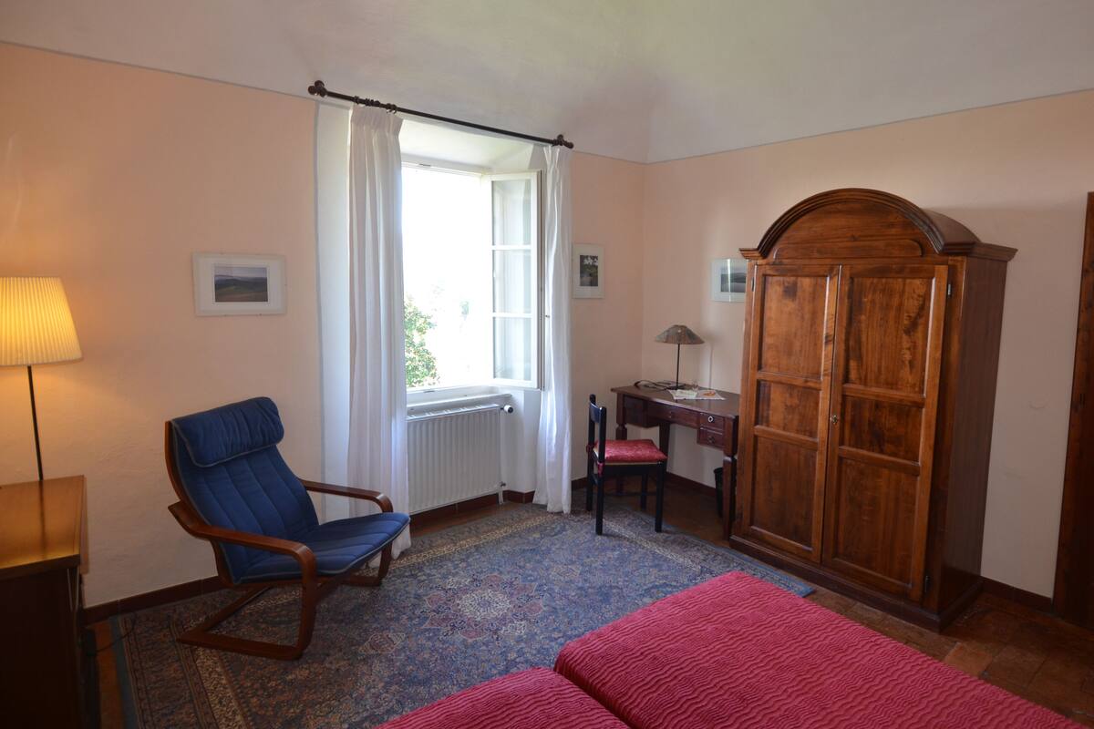 Een slaapkamer met een bed, een stoel, een bureau en een kledingkast.