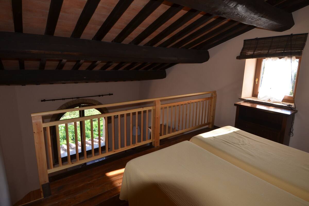 Een slaapkamer met een houten bed, een raam met zonwering en een houten leuning.