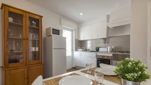Una cocina moderna con armarios blancos, microondas integrado y refrigerador de acero inoxidable.