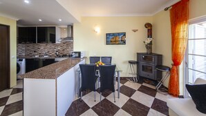 A modern kitchen with a granite countertop, a dining area with chairs, a stove, and a sink. - B47 - Walkway Beachview Place (Lagos)