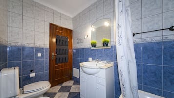 A bathroom with a toilet, sink, and shower area.