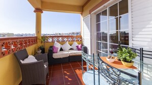 A balcony with a sofa, chairs, a table, and potted plants. - B47 - Walkway Beachview Place (Lagos)