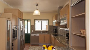 A kitchen with granite countertops, stainless steel appliances, and wooden cabinets. - D07 - Torraltinha Villa in Lagos (Lagos)