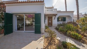 A house with a tiled patio, green shutters, and a garden with various plants. - D07 - Torraltinha Villa in Lagos (Lagos)