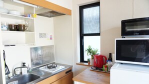 Une cuisine compacte équipée d’un évier, d’une cuisinière et d’un four à micro-ondes. Une fenêtre offre une vue sur l’extérieur.