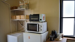 Une petite cuisine équipée avec un réfrigérateur blanc, un four à micro-ondes et une machine à café, le tout posé sur un plan de travail en bois.