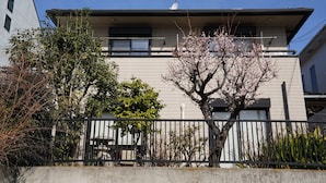 Un immeuble d’habitation doté d’un toit plat, d’une antenne parabolique et d’un arbre aux fleurs roses.
