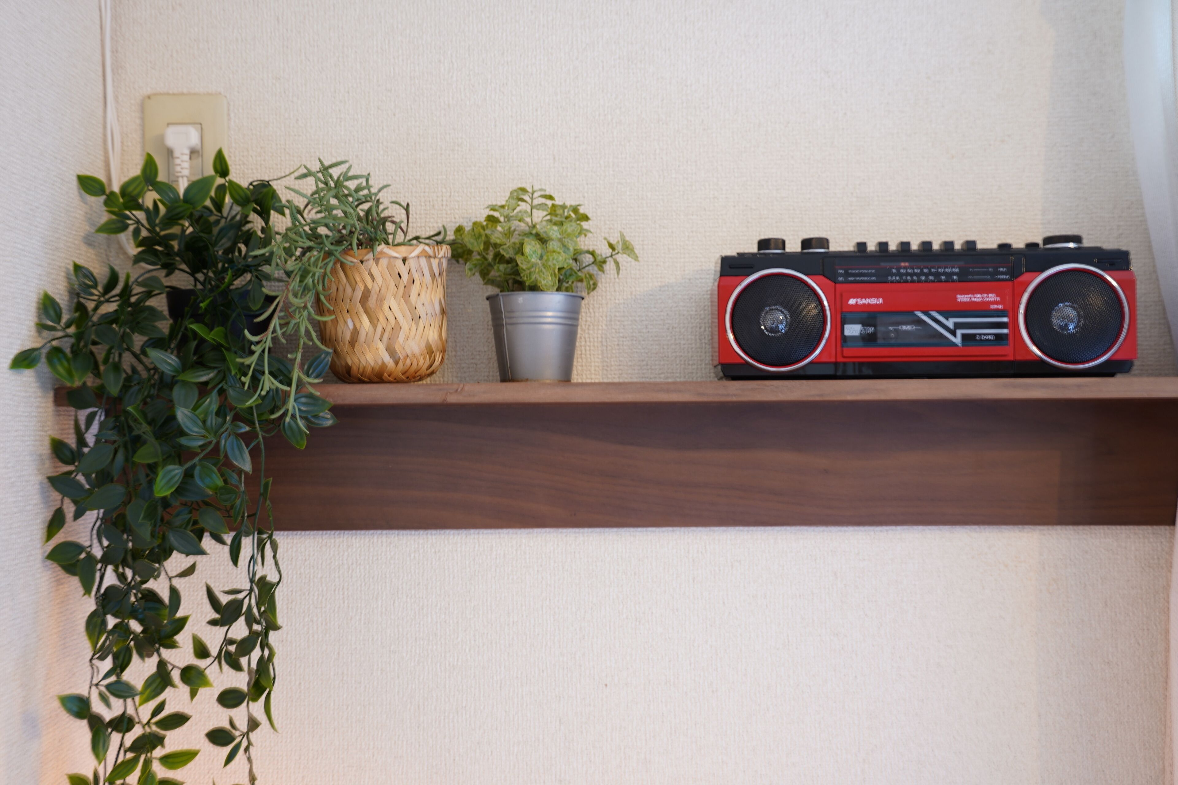 A shelf with a red radio, a woven basket, and a potted plant.
