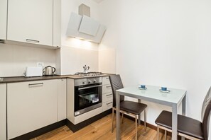 A compact kitchen with a stove, oven, and a small dining table with chairs.