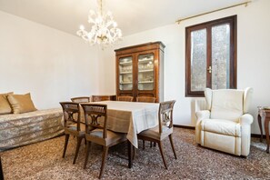 A dining area with a table, chairs, a cabinet, a sofa, and a window.