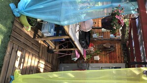 Una terraza de madera con varios objetos, como una maceta verde, un paño azul y una planta colgante.