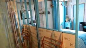 Una habitación con una cama, una mesita y una silla. Hay cortinas y una ventana.