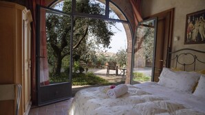 Een slaapkamer met een groot raam, een bed en uitzicht op een tuin.