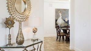 Un área de comedor con una mesa y sillas, un espejo decorativo y un cuadro en la pared.