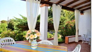 A covered patio with a table, chairs, and a vase of flowers. - New valmar Villa Camboni (Costa Rei)
